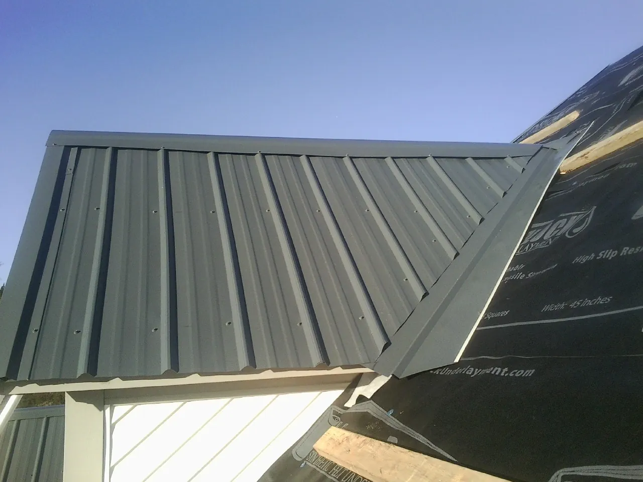 Gray metal roof panels going on over a garage gable in Grand Forks