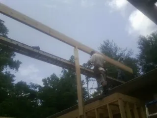 Carpenter setting a ridge beam over a new addition frame — Ice Dam Removal by Roofing Brothers in Grand Forks