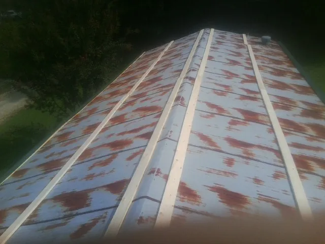 Rusted metal roof panels with new wood purlins before replacement — Storm Damage Roof Repair in Grand Forks by Roofing Brothers