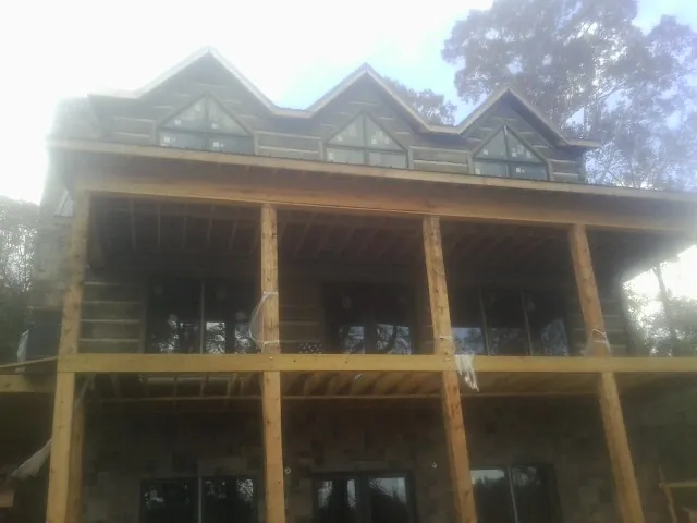 Dormers and porch framing on a large log home under construction — Roof Coating work by our crew in Grand Forks