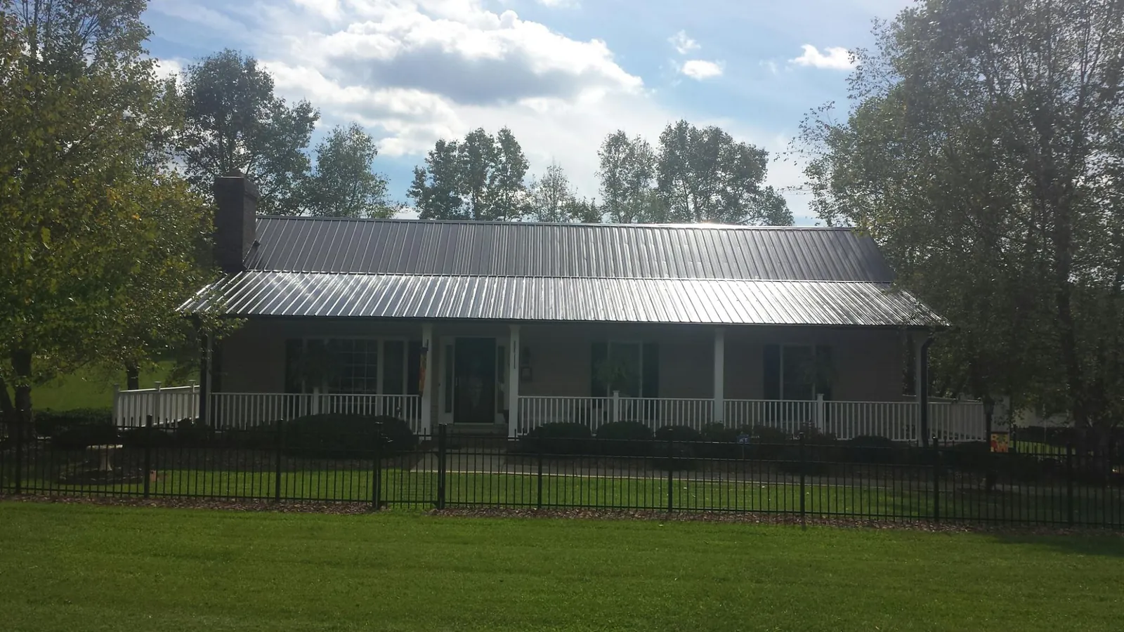 Gray metal roof on a brick ranch with a full width front porch — Gutter Guard Installation work by our crew in Grand Forks