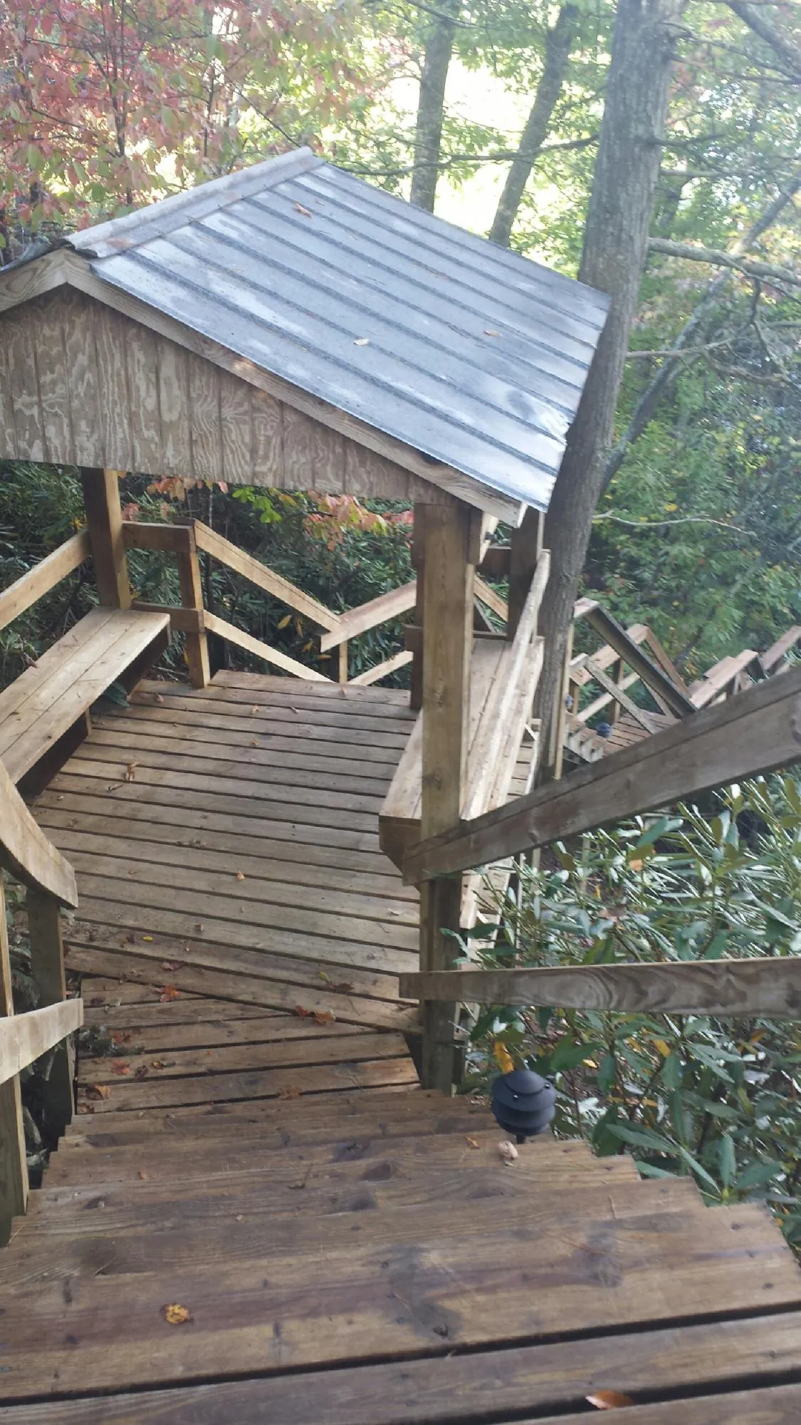 Metal roofed shelter over wooden steps on a wooded walkway — Skylight Repair & Installation work by our crew in Grand Forks