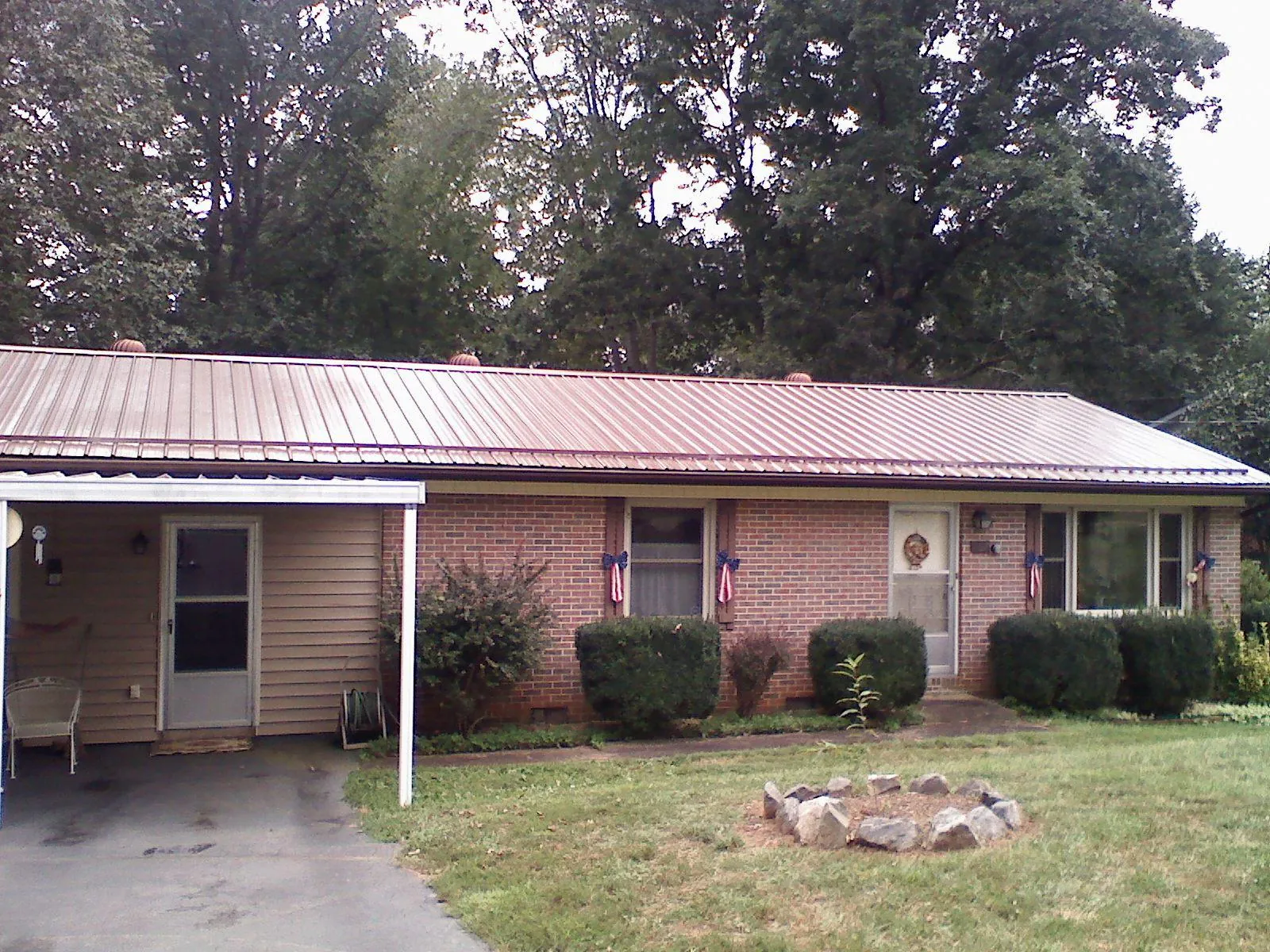 Bronze metal roof and carport on a brick ranch home — Roof Repair work by our crew in Grand Forks