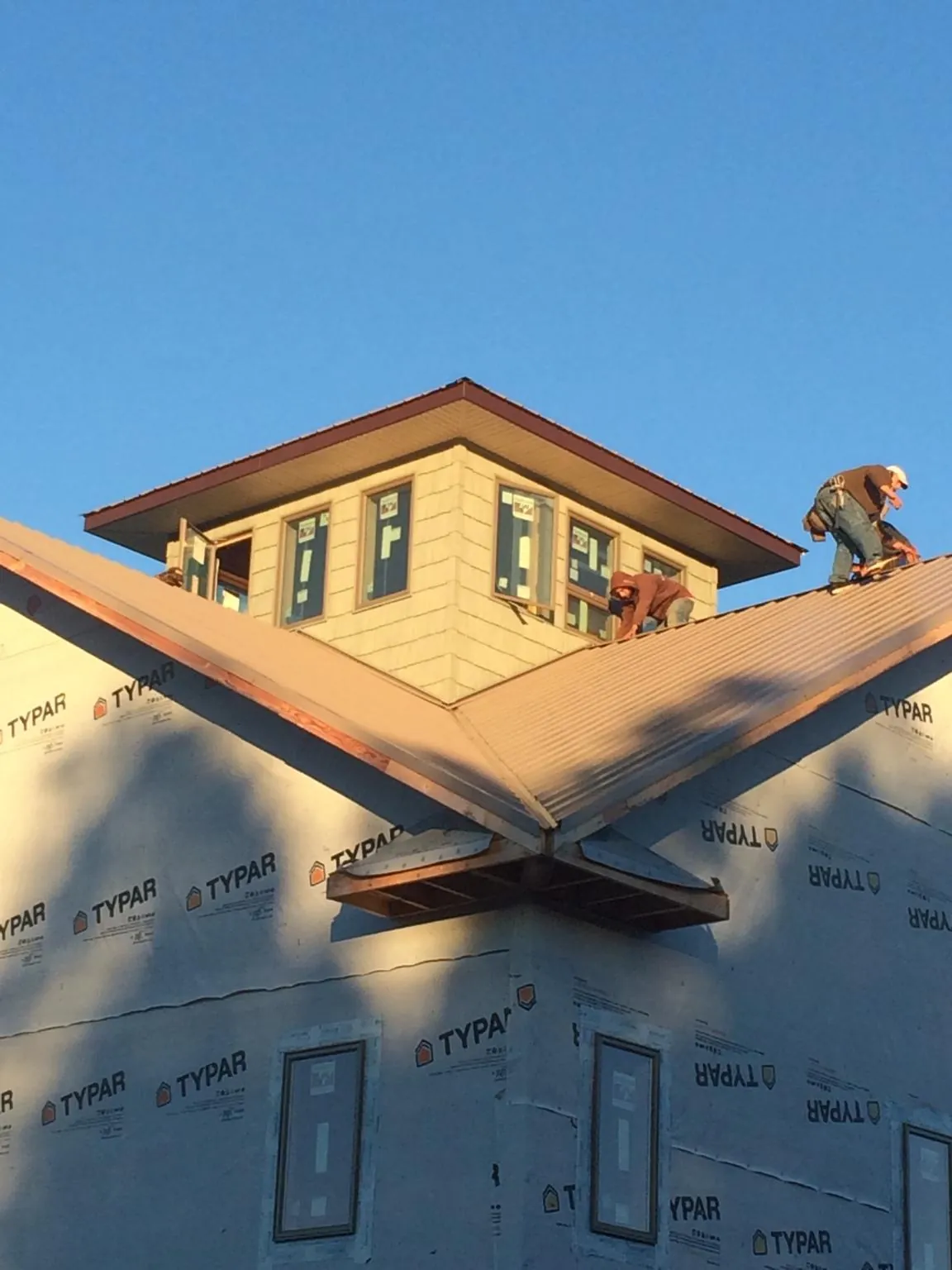 Roofers working around a rooftop cupola on a new metal roof at sunset — Roof Waterproofing in Grand Forks by Roofing Brothers